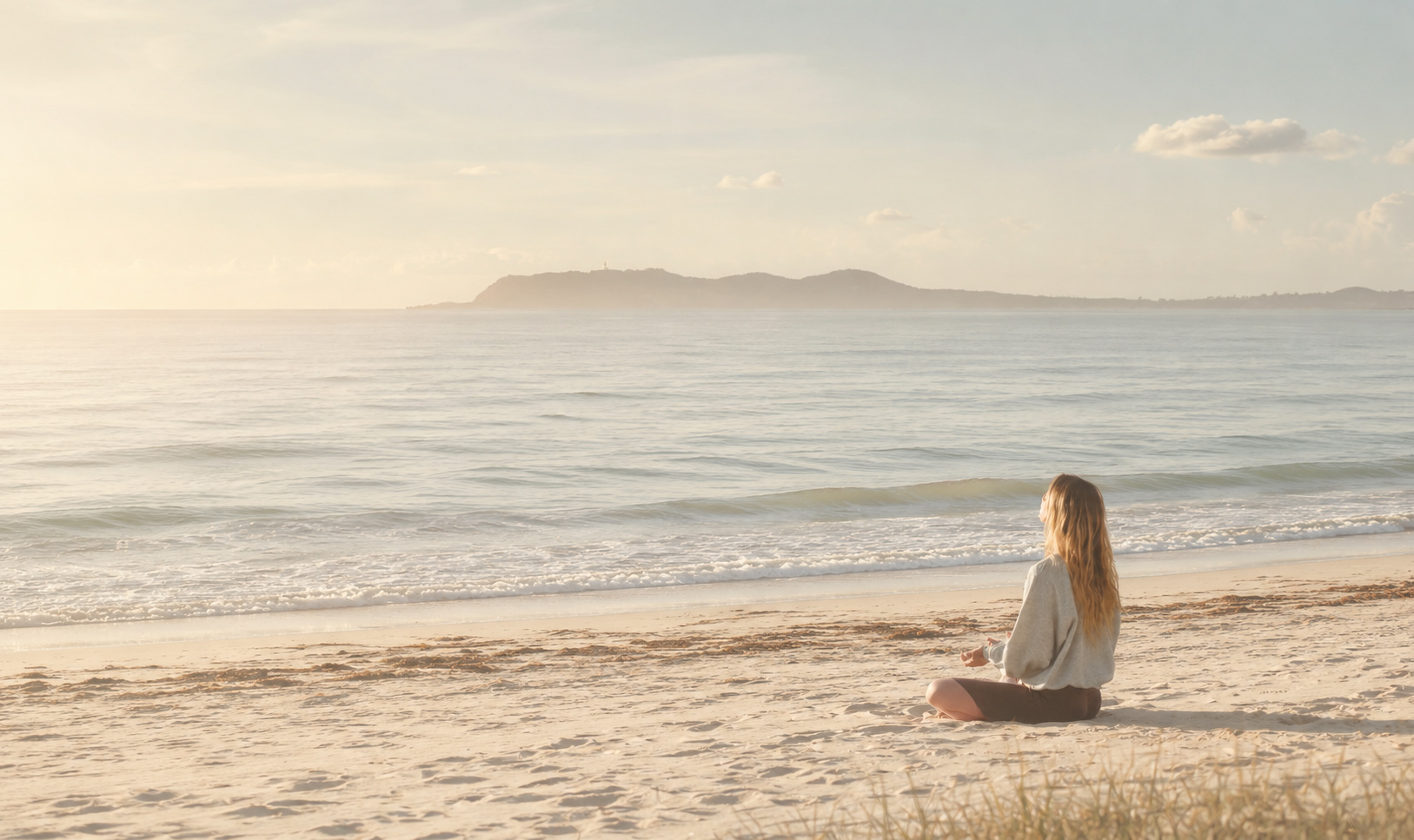 A woman sitting quietly by the sea in soft morning light