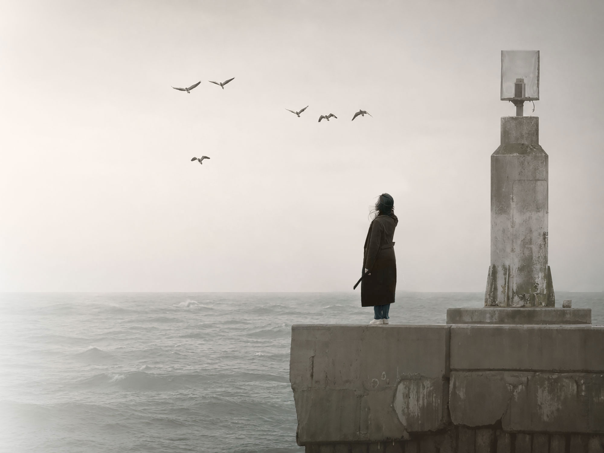 A woman sitting quietly by the sea in soft morning light